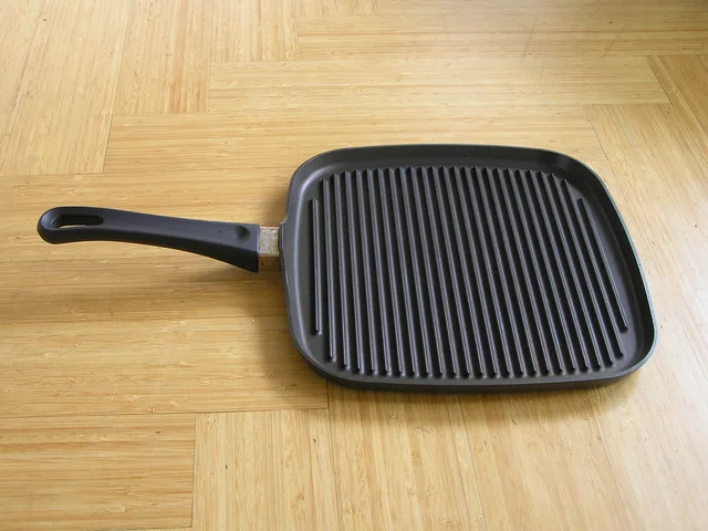 Square grill pan with raised parallel ribs and a long handle