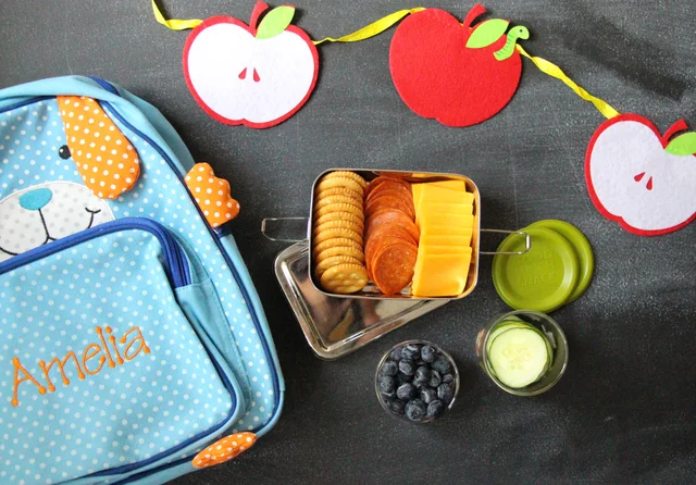 Blue personalised lunch bag beside a steel snack box and small food containers