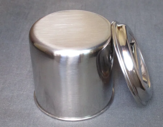 Upside-down stainless steel kitchen pot with its separate lid alongside